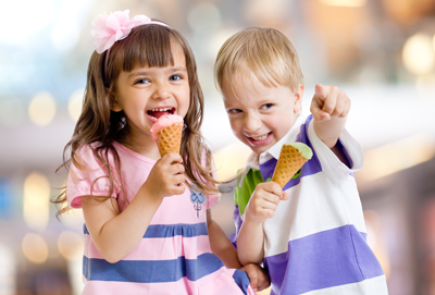 Two children smiling and holding ice cream cones representing positive childhood development and empowerment programs.